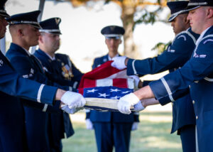 soldiers handing folded American flag to Veteran's wife at Arlington National Cemetery funeral